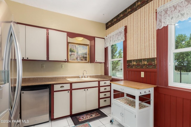 kitchen with light tile patterned flooring, sink, white cabinetry, and stainless steel appliances