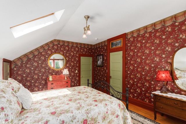 bedroom with hardwood / wood-style floors and lofted ceiling with skylight