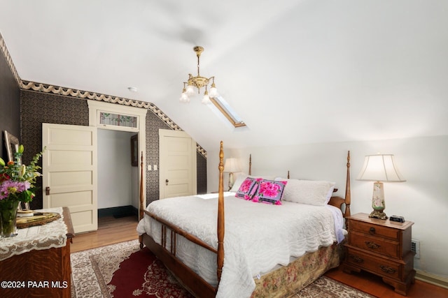 bedroom featuring lofted ceiling, wood-type flooring, and a chandelier