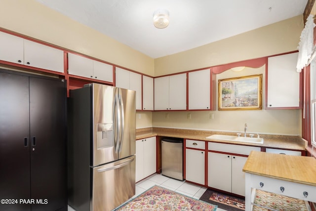 kitchen with white cabinets, appliances with stainless steel finishes, light tile patterned flooring, and sink