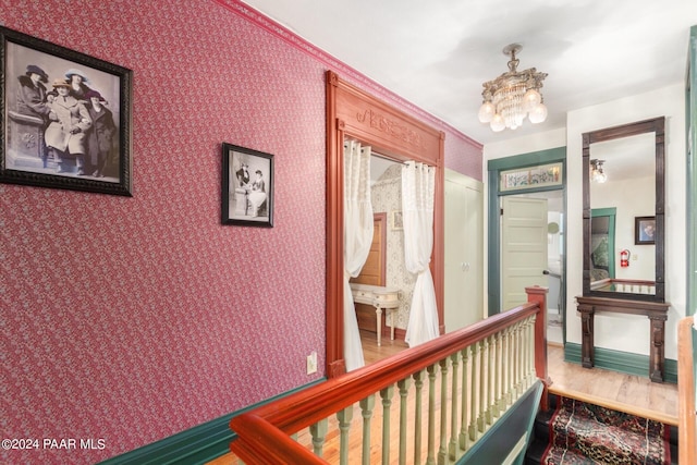 hallway featuring hardwood / wood-style floors, a notable chandelier, and ornamental molding