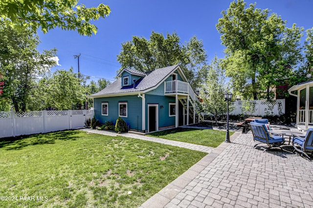 back of house with a yard, a patio area, and a balcony