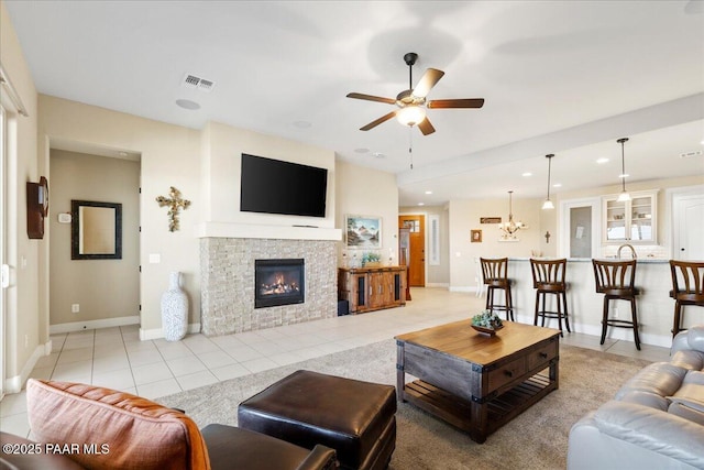 living room with baseboards, visible vents, a ceiling fan, a fireplace, and light tile patterned flooring