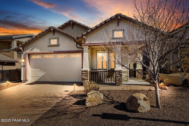 craftsman house with an attached garage, a tile roof, stone siding, decorative driveway, and stucco siding