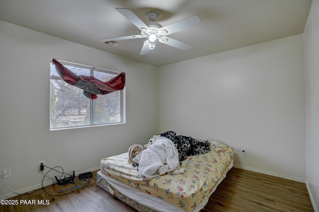 bedroom with baseboards, visible vents, ceiling fan, and wood finished floors