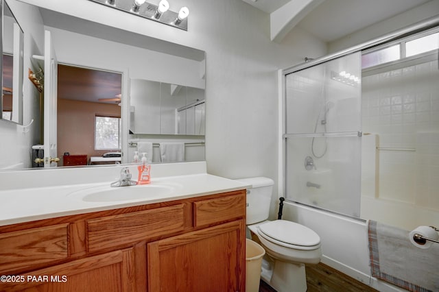 full bathroom with combined bath / shower with glass door, wood finished floors, toilet, and vanity