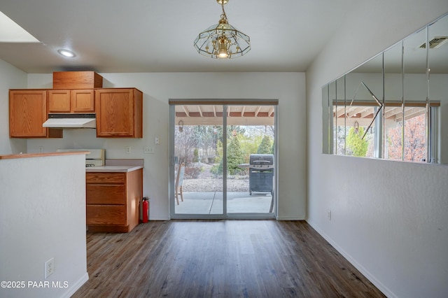 kitchen with brown cabinets, visible vents, under cabinet range hood, and a healthy amount of sunlight