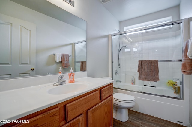 bathroom with toilet, vanity, enclosed tub / shower combo, and wood finished floors