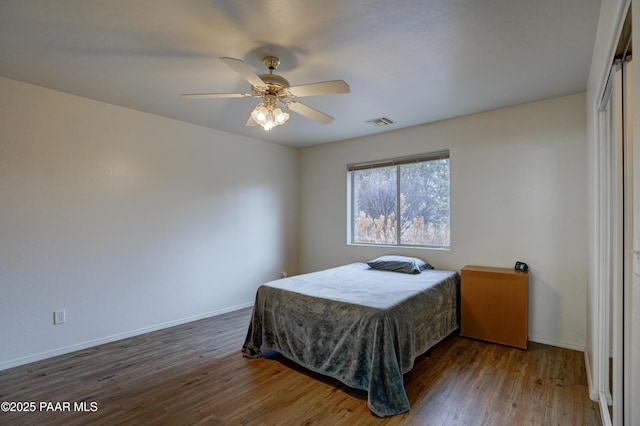 bedroom with baseboards, visible vents, a ceiling fan, and wood finished floors