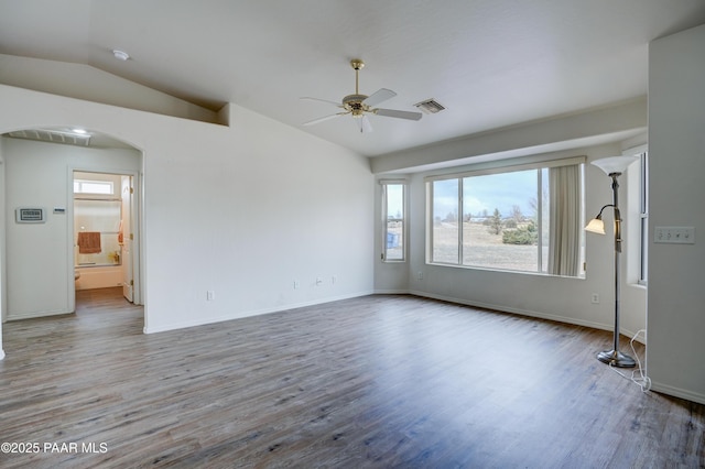 unfurnished room with vaulted ceiling, a ceiling fan, wood finished floors, visible vents, and arched walkways
