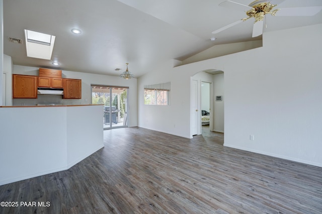unfurnished living room featuring lofted ceiling, arched walkways, visible vents, a ceiling fan, and wood finished floors