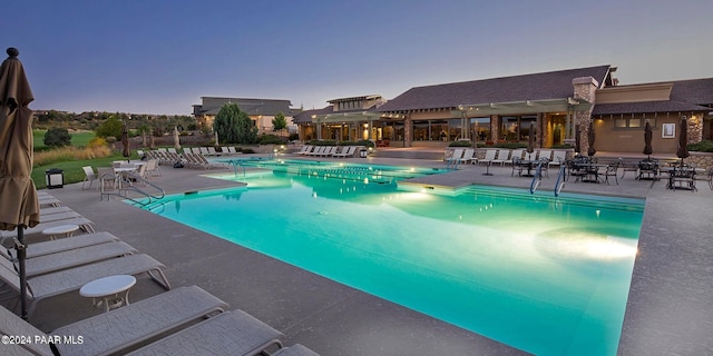 pool at dusk with a patio area