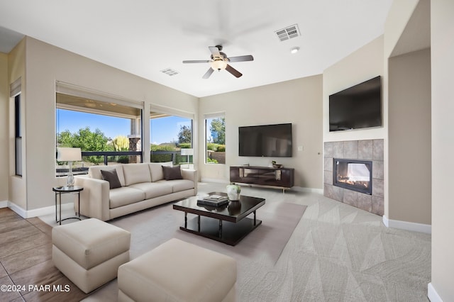 carpeted living room featuring a tile fireplace and ceiling fan