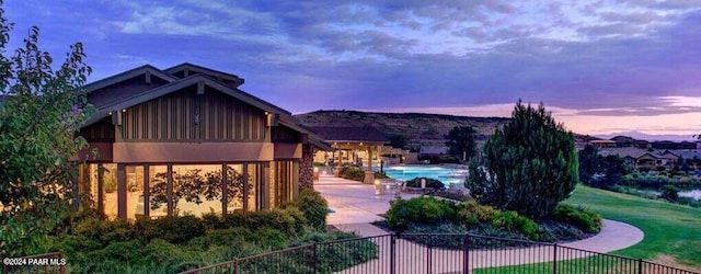 pool at dusk featuring a lawn