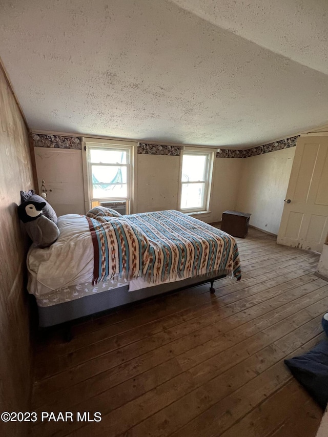 bedroom with hardwood / wood-style flooring, a textured ceiling, and multiple windows