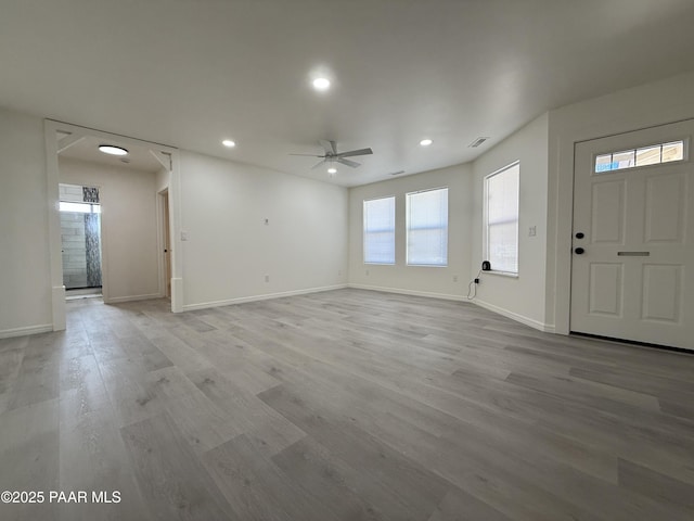 unfurnished living room featuring ceiling fan, a healthy amount of sunlight, and light wood-type flooring