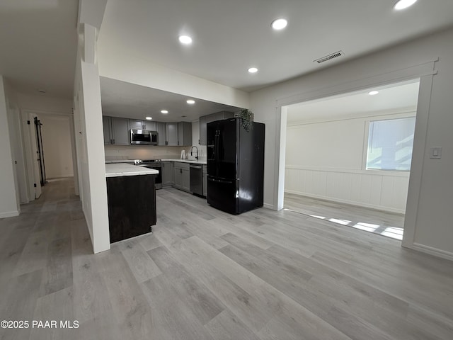 kitchen with appliances with stainless steel finishes, gray cabinets, and light wood-type flooring