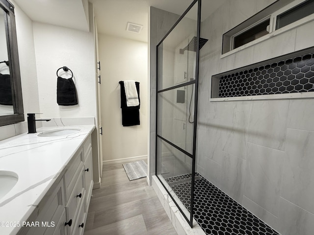 bathroom with tiled shower, wood-type flooring, and vanity