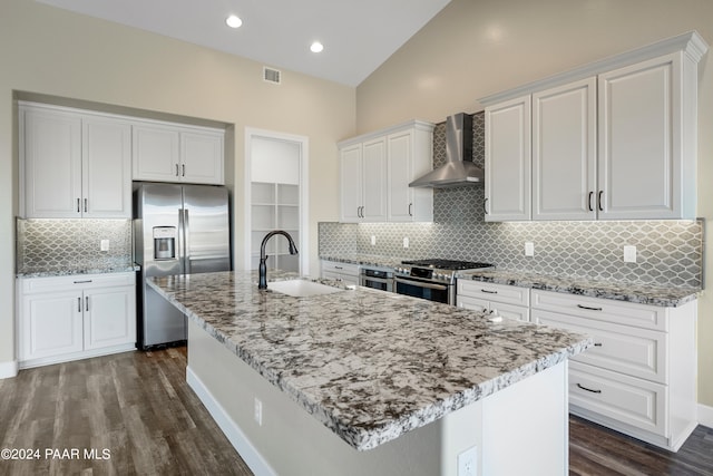 kitchen with sink, a center island with sink, wall chimney range hood, and appliances with stainless steel finishes