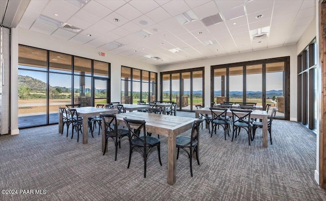 dining space with a mountain view, dark carpet, and a drop ceiling