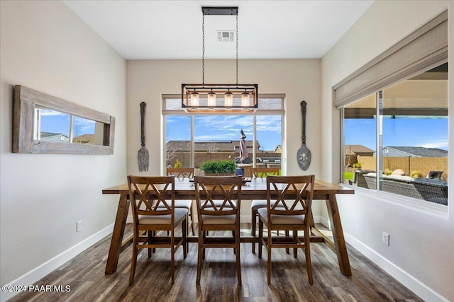 dining space with dark hardwood / wood-style flooring and an inviting chandelier