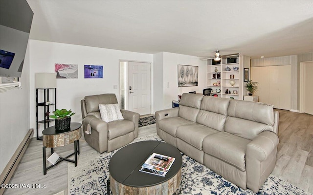 living room featuring a baseboard heating unit, light wood-type flooring, a ceiling fan, and baseboards