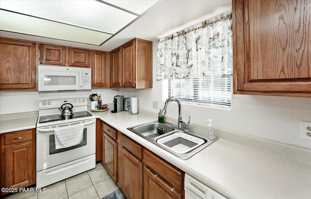 kitchen featuring light tile patterned floors, white appliances, a sink, and brown cabinets