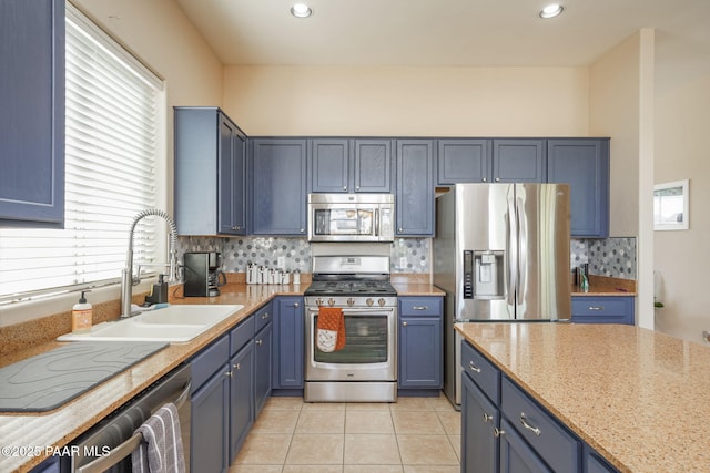 kitchen featuring blue cabinets, tasteful backsplash, a sink, light tile patterned floors, and stainless steel appliances