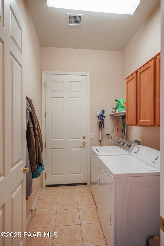 clothes washing area with cabinet space, visible vents, light tile patterned floors, and washing machine and clothes dryer
