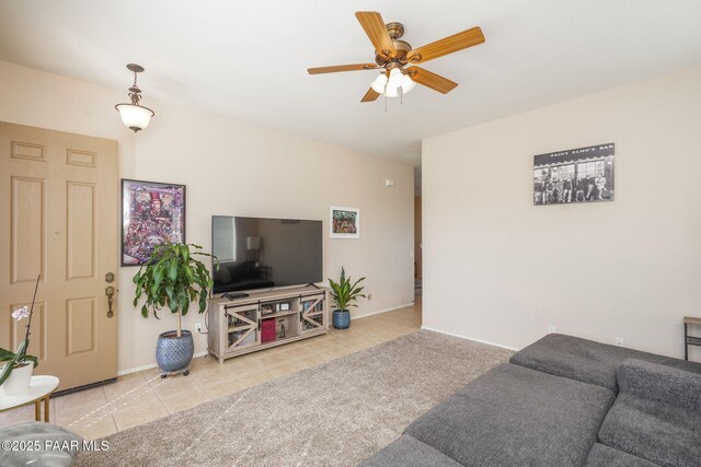 tiled living area with ceiling fan and baseboards