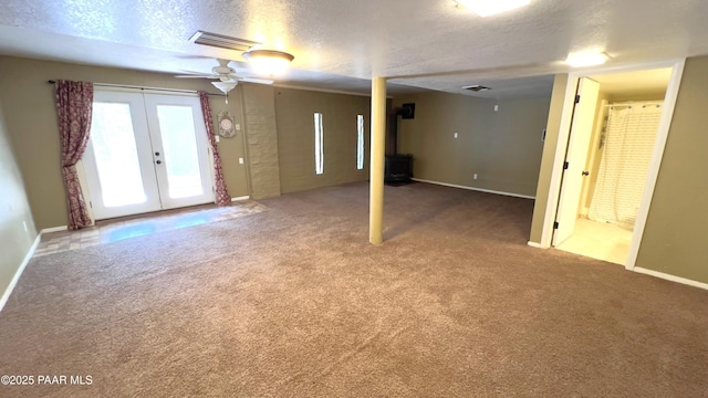 885 S Rancho Vista Dr, Prescott, AZ 86303 - unfurnished living room with a wood stove, a textured ceiling, carpet flooring, baseboards, and french doors