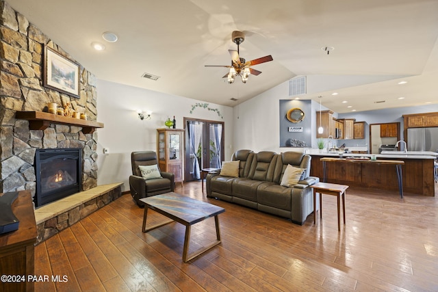 living room featuring hardwood / wood-style flooring, ceiling fan, lofted ceiling, and a fireplace