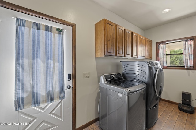 washroom featuring light wood-type flooring, washing machine and dryer, and cabinets