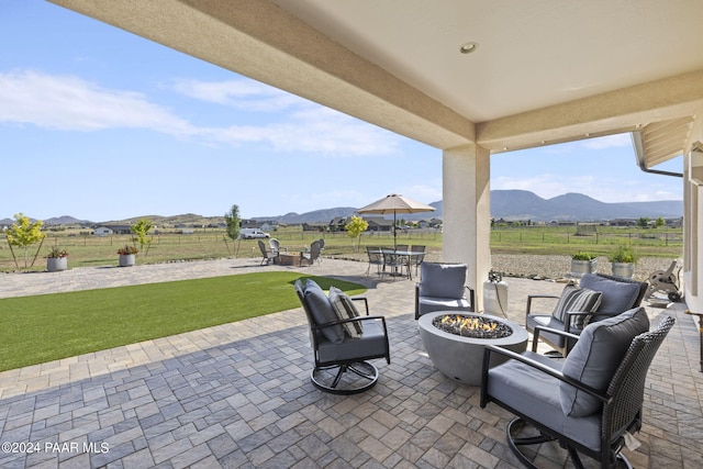 view of patio / terrace with a mountain view and an outdoor living space with a fire pit