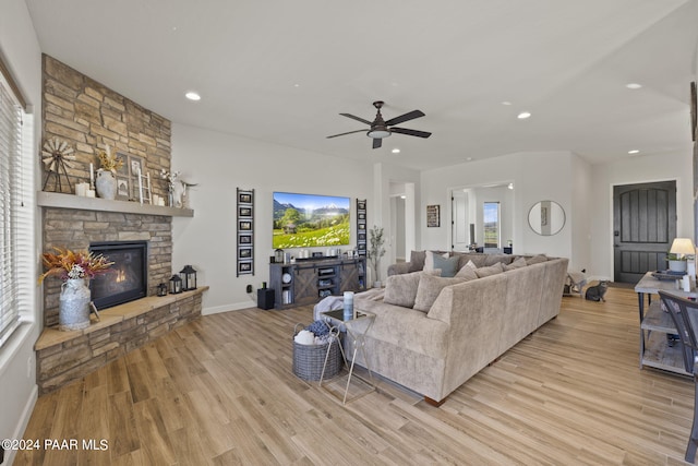 living room featuring ceiling fan, a fireplace, and light hardwood / wood-style floors