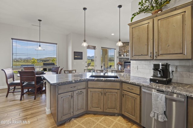 kitchen featuring sink, hanging light fixtures, stainless steel dishwasher, kitchen peninsula, and light hardwood / wood-style floors