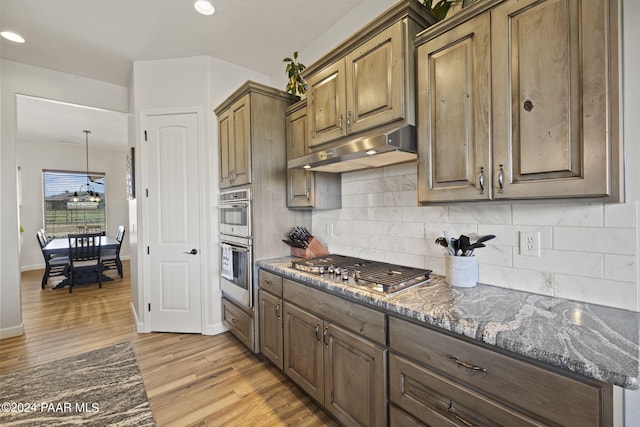 kitchen with tasteful backsplash, light hardwood / wood-style floors, stainless steel appliances, and dark stone countertops