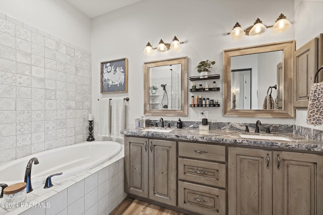 bathroom with tiled tub, vanity, and wood-type flooring