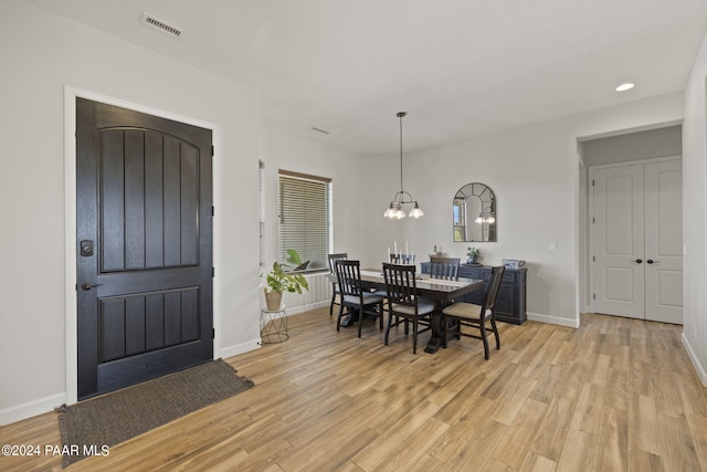 dining area with a notable chandelier and light hardwood / wood-style flooring