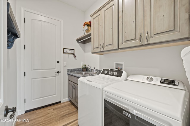 laundry room with cabinets, independent washer and dryer, sink, and light hardwood / wood-style flooring