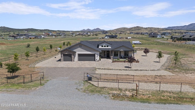 view of front of property with a mountain view, covered porch, a rural view, and a garage