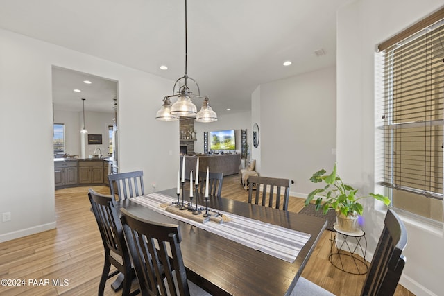 dining area with light hardwood / wood-style floors, sink, and a fireplace