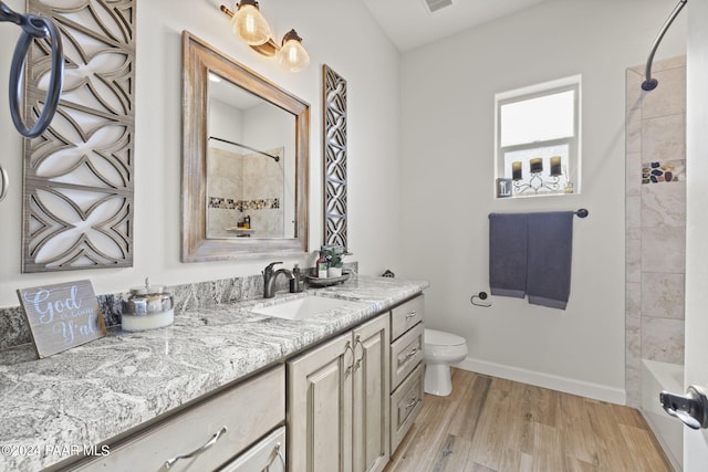 full bathroom with hardwood / wood-style floors, vanity, toilet, and tiled shower / bath