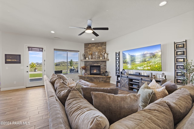 living room with ceiling fan, a fireplace, and light wood-type flooring