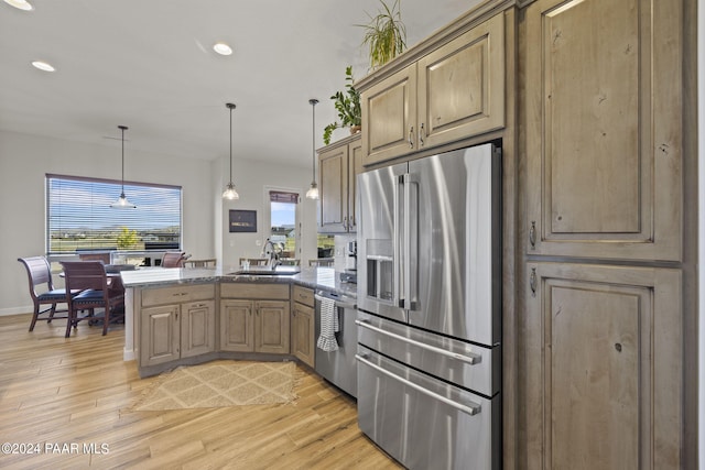 kitchen with sink, hanging light fixtures, light wood-type flooring, appliances with stainless steel finishes, and kitchen peninsula