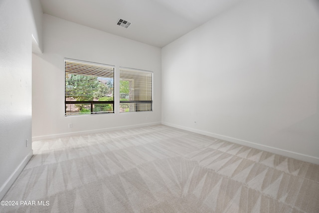 carpeted spare room featuring high vaulted ceiling