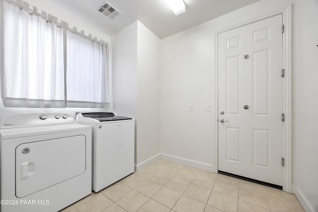 clothes washing area with separate washer and dryer and light tile patterned floors