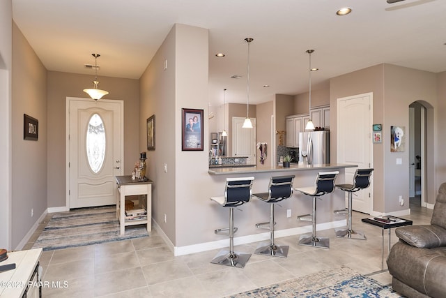 interior space featuring arched walkways, recessed lighting, a peninsula, a kitchen breakfast bar, and stainless steel fridge