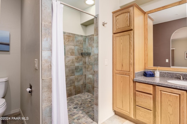 bathroom featuring tile patterned flooring, vanity, toilet, and curtained shower