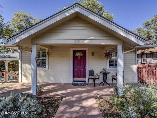 property entrance with a porch and fence